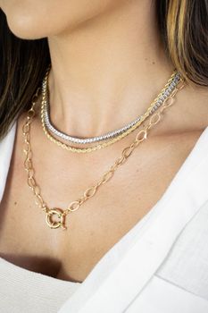 Close-up image showcasing elegant gold and silver necklaces on a woman's neck.