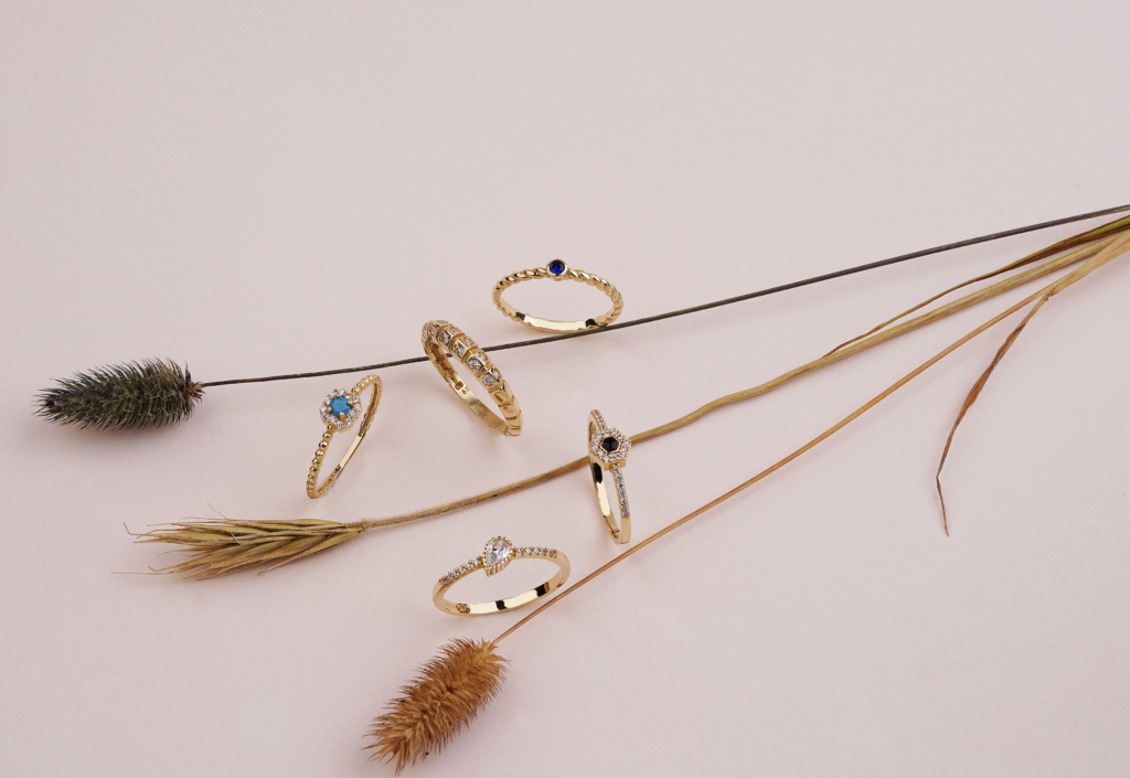 A flat lay of elegant gold rings adorned with gemstones, resting on natural twigs.