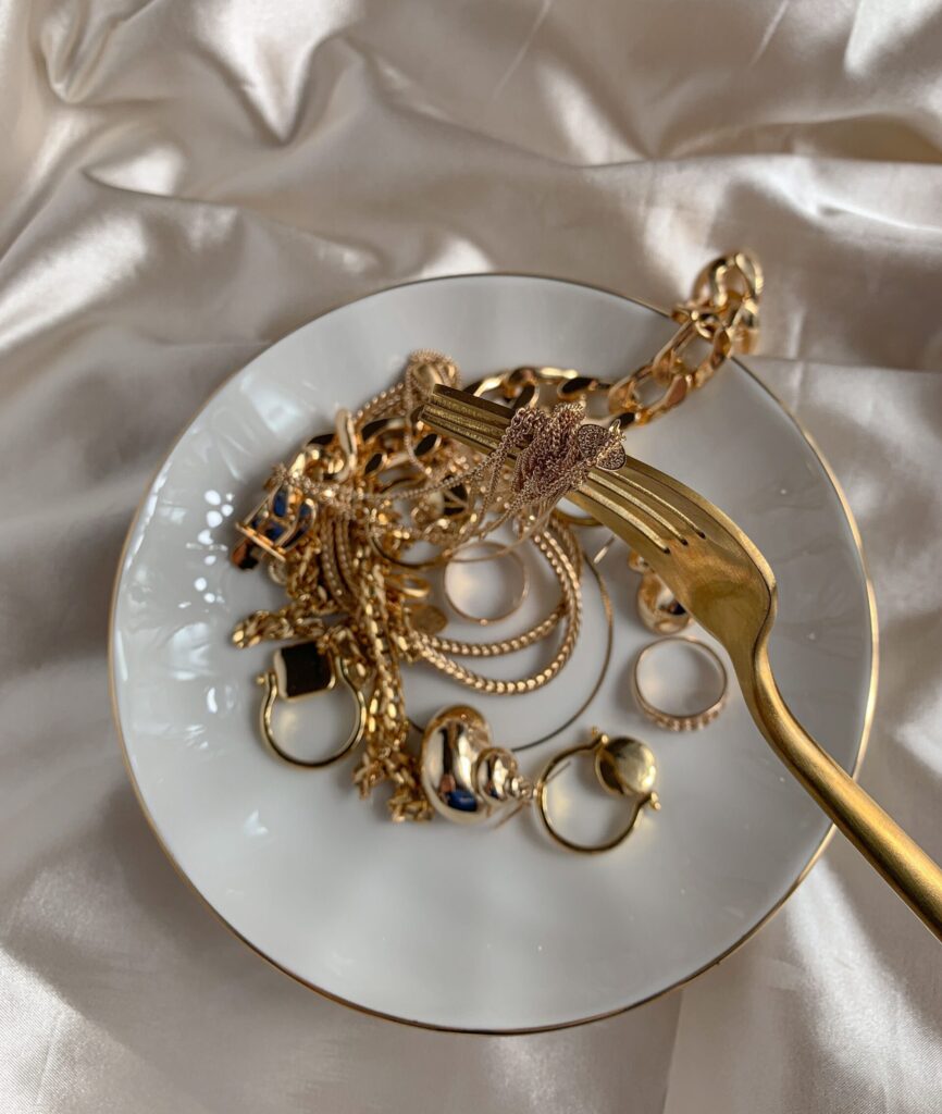 A collection of gold jewelry elegantly displayed on a white plate with a satin background.