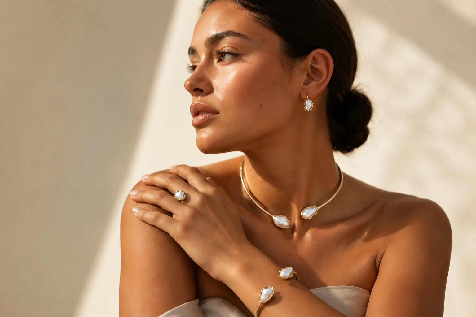 Home A model posing in warm sunlight while wearing elegant, pearl-adorned gold anti tarnish jewellery.