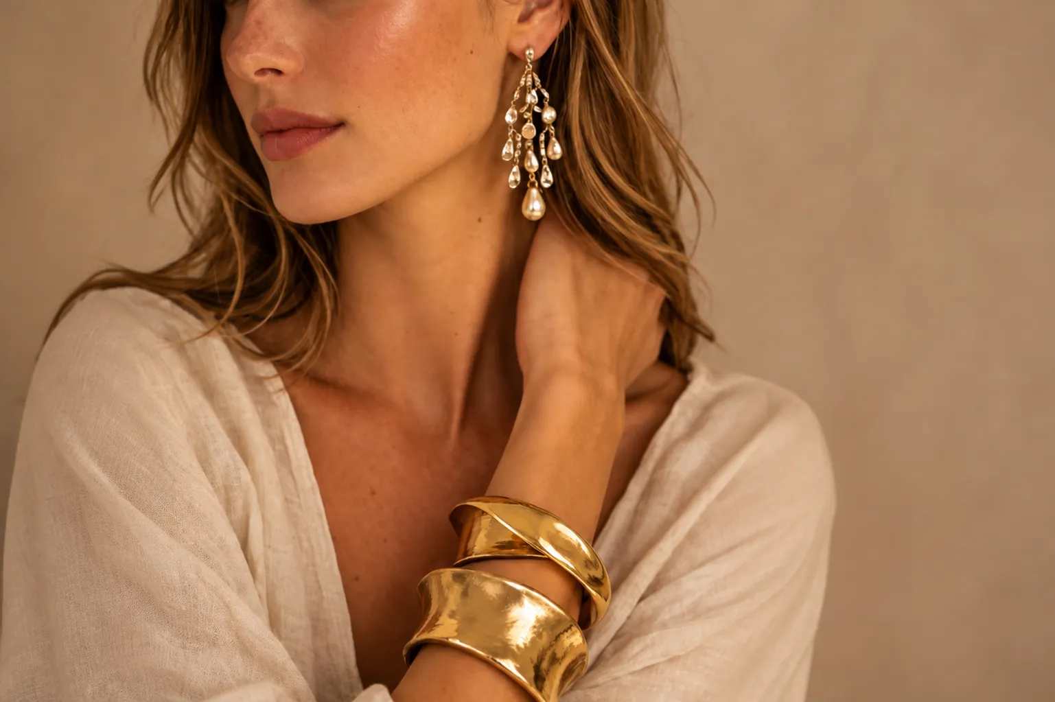 Elegant gold cuffs and pearl drop earrings styled with a flowing white outfit, showcasing anti tarnish jewellery with timeless elegance.